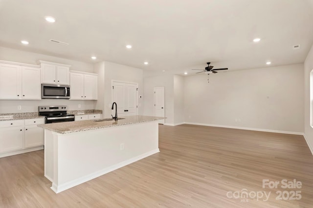1041 Russell Dr, Winston Salem, NC 27127 - kitchen with stainless steel microwave, electric range, ceiling fan, a center island with sink, and light wood-style flooring