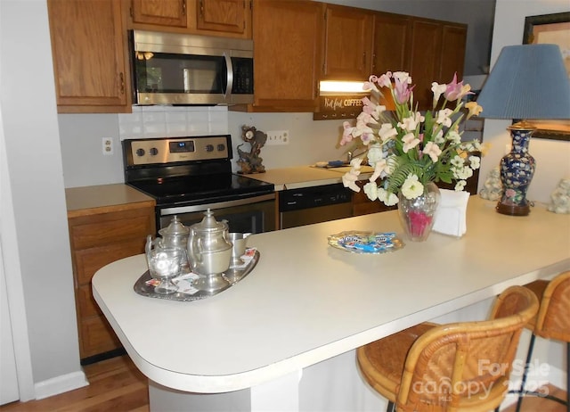 6148 Meadow Rose Ln, Charlotte, NC 28215 - kitchen with stainless steel appliances, light countertops, a kitchen bar, and brown cabinets