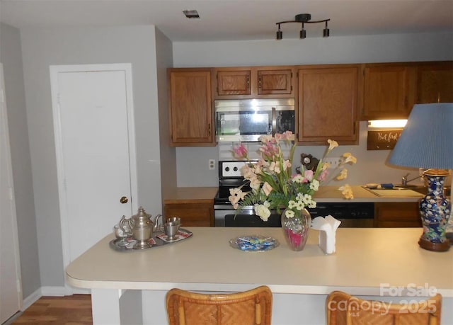 6148 Meadow Rose Ln, Charlotte, NC 28215 - kitchen featuring stainless steel appliances, light countertops, and brown cabinetry