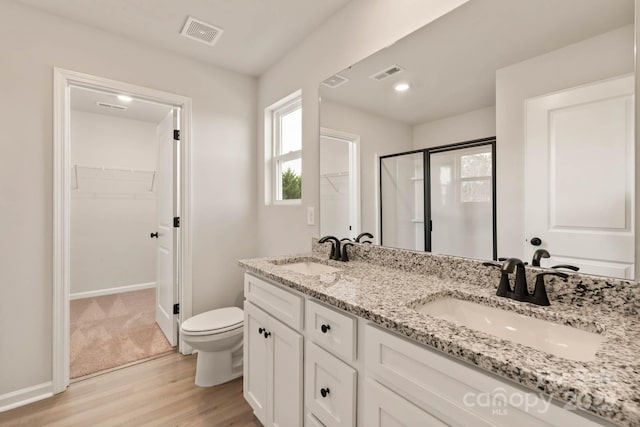 1048 Russell Dr, Winston Salem, NC 27127 - bathroom with a walk in closet, wood finished floors, double vanity, and a shower stall