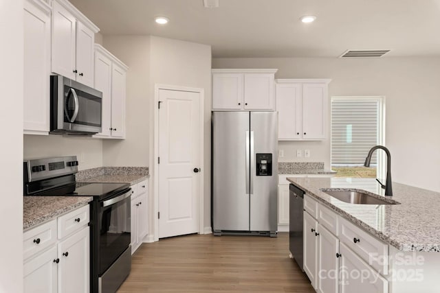 1048 Russell Dr, Winston Salem, NC 27127 - kitchen featuring appliances with stainless steel finishes, white cabinets, light wood-type flooring, recessed lighting, and light stone counters