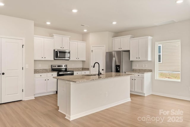 1048 Russell Dr, Winston Salem, NC 27127 - kitchen featuring appliances with stainless steel finishes, light wood-style floors, white cabinets, a kitchen island with sink, and recessed lighting