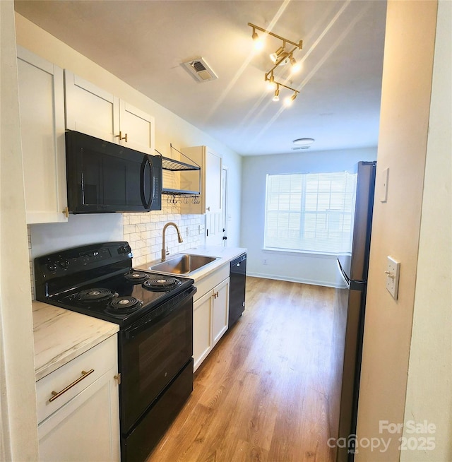 3106 Faircroft Way, Monroe, NC 28110 - kitchen featuring black appliances, light wood-style flooring, decorative backsplash, white cabinetry, and rail lighting