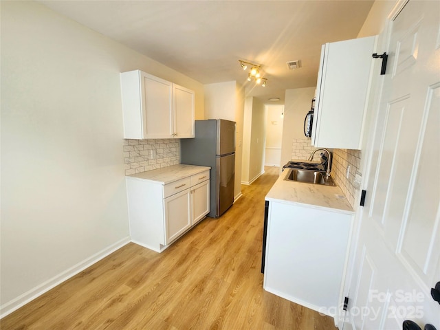 3106 Faircroft Way, Monroe, NC 28110 - kitchen with freestanding refrigerator, tasteful backsplash, light wood-style flooring, and white cabinetry