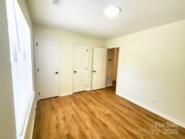 3106 Faircroft Way, Monroe, NC 28110 - unfurnished bedroom with light wood-style floors and multiple closets
