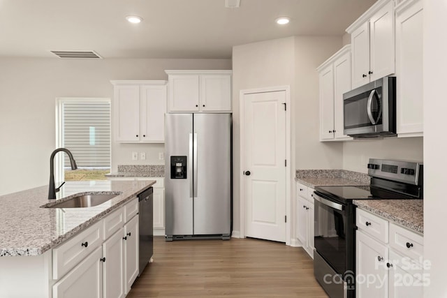 1072 Russell Dr, Winston Salem, NC 27127 - kitchen featuring appliances with stainless steel finishes, white cabinetry, light wood-style flooring, recessed lighting, and light stone countertops
