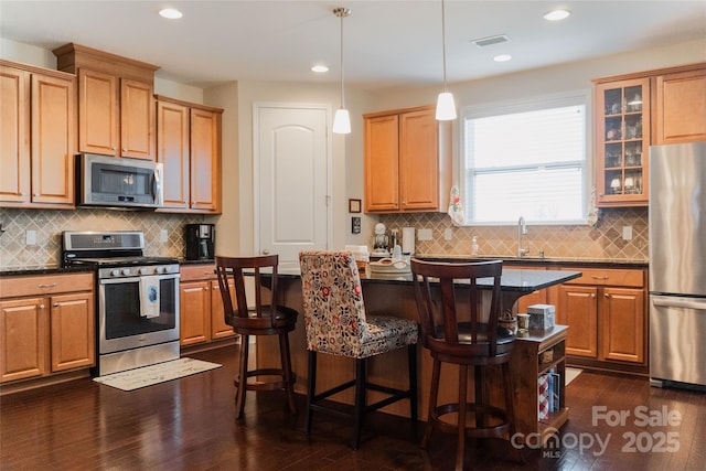 1156 Mckee Farm Ln, Belmont, NC 28012 - kitchen with appliances with stainless steel finishes, dark wood finished floors, a kitchen breakfast bar, backsplash, and recessed lighting