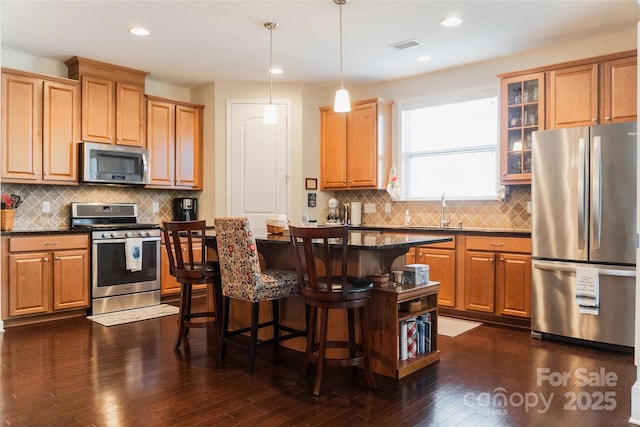 1156 Mckee Farm Ln, Belmont, NC 28012 - kitchen featuring appliances with stainless steel finishes, a kitchen breakfast bar, dark wood finished floors, glass insert cabinets, and decorative backsplash