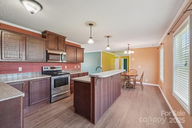 1069 Heather Glen Dr, Catawba, NC 28609 - kitchen featuring appliances with stainless steel finishes, light wood finished floors, ornamental molding, light countertops, and a center island with sink