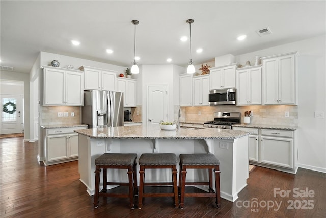 10120 Berkeley Castle Dr, Charlotte, NC 28273 - kitchen with stainless steel appliances, white cabinets, decorative backsplash, a center island with sink, and a kitchen bar