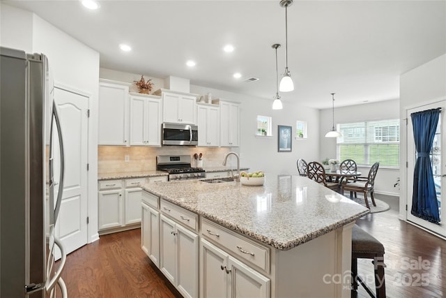 10120 Berkeley Castle Dr, Charlotte, NC 28273 - kitchen with appliances with stainless steel finishes, dark wood-style flooring, a breakfast bar, white cabinets, and pendant lighting