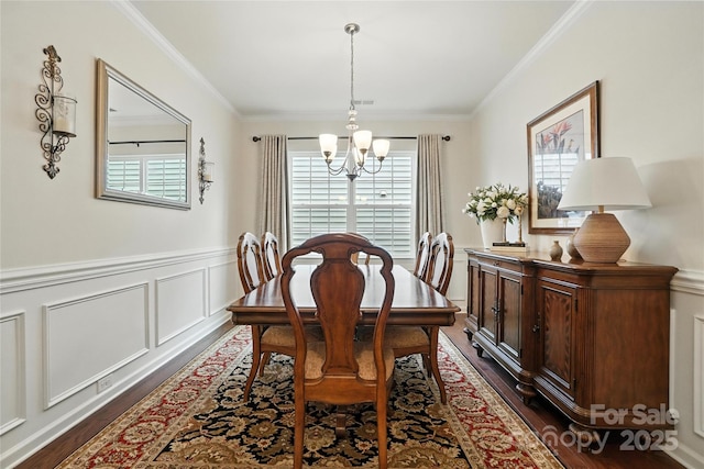 10120 Berkeley Castle Dr, Charlotte, NC 28273 - dining space with a chandelier, crown molding, dark wood-style floors, wainscoting, and a decorative wall