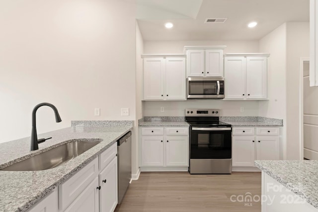 1060 Russell Dr, Winston Salem, NC 27127 - kitchen with appliances with stainless steel finishes, white cabinets, light wood finished floors, recessed lighting, and light stone countertops