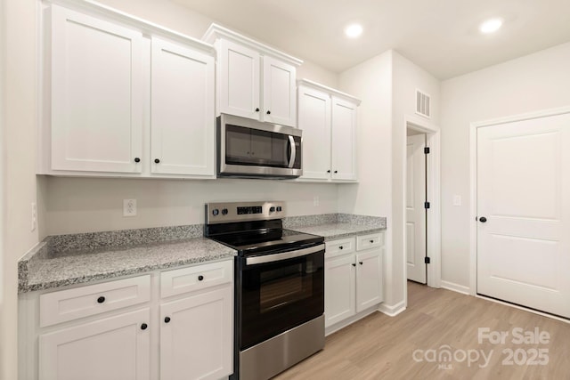 1060 Russell Dr, Winston Salem, NC 27127 - kitchen with appliances with stainless steel finishes, light wood finished floors, white cabinetry, recessed lighting, and light stone countertops