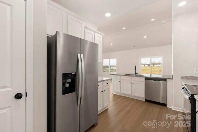 1060 Russell Dr, Winston Salem, NC 27127 - kitchen with stainless steel appliances, light wood-style flooring, white cabinetry, a peninsula, and recessed lighting