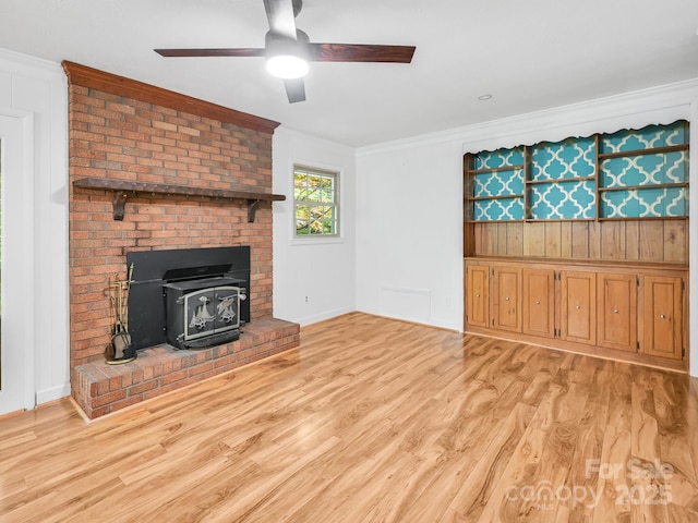 8 Mayfair Dr, Candler, NC 28715 - unfurnished living room with crown molding, a wood stove, a ceiling fan, and light wood-style floors