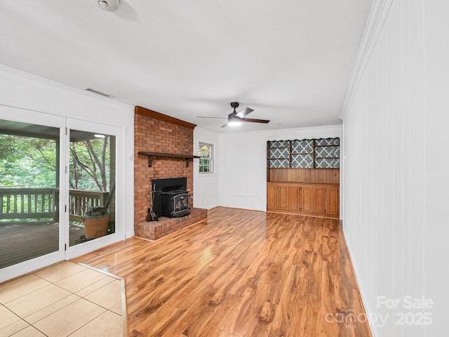 8 Mayfair Dr, Candler, NC 28715 - unfurnished living room with ornamental molding, a wood stove, wood finished floors, a ceiling fan, and wood walls