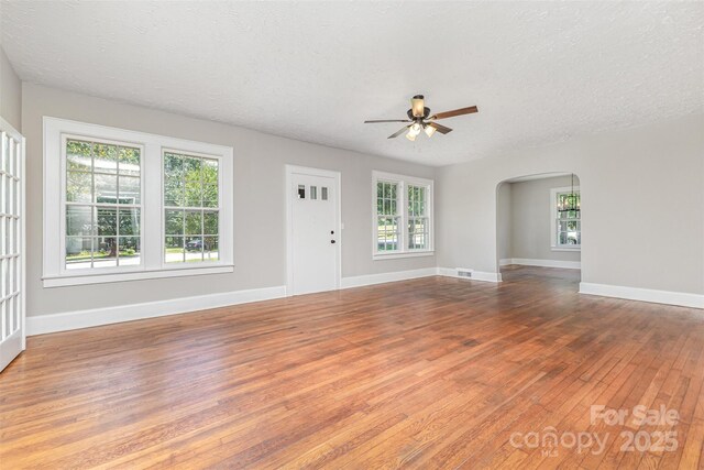 309 E Main St, Lattimore, NC 28089 - unfurnished living room with ceiling fan, hardwood / wood-style flooring, arched walkways, and a textured ceiling