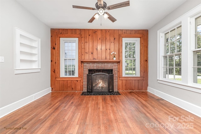 309 E Main St, Lattimore, NC 28089 - unfurnished living room with wood finished floors, a brick fireplace, ceiling fan, built in shelves, and wooden walls