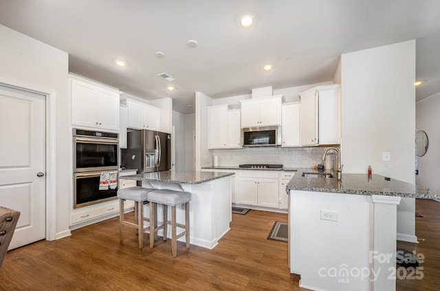 5580 Soft Shell Dr, Lancaster, SC 29720 - kitchen with stainless steel appliances, a breakfast bar, white cabinets, dark stone counters, and recessed lighting