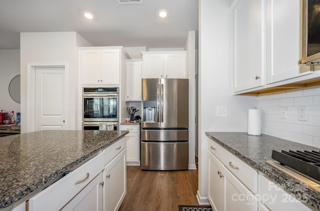 5580 Soft Shell Dr, Lancaster, SC 29720 - kitchen featuring stainless steel appliances, white cabinetry, dark wood finished floors, tasteful backsplash, and dark stone countertops