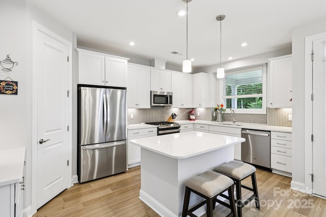 3022 Trace Meadow Ct, York, SC 29745 - kitchen featuring appliances with stainless steel finishes, light wood-style floors, decorative backsplash, white cabinetry, and a center island