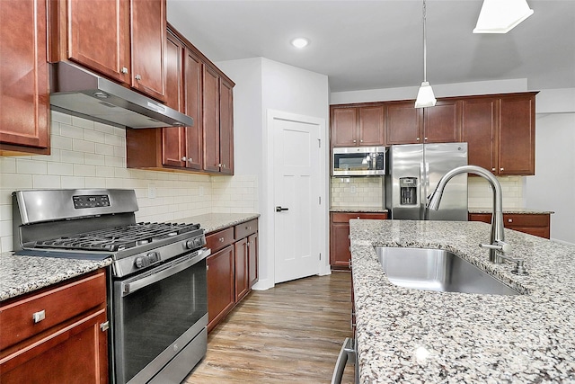 7079 Waterwheel St SW, Concord, NC 28025 - kitchen with stainless steel appliances, under cabinet range hood, light wood-type flooring, backsplash, and light stone countertops
