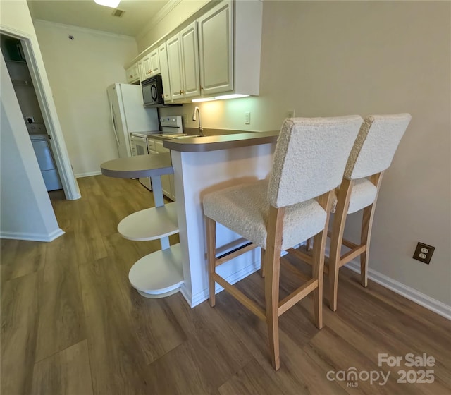 1410 4th Street Dr NW Unit 303, Hickory, NC 28601 - kitchen featuring white appliances, dark wood finished floors, a breakfast bar area, crown molding, and a peninsula