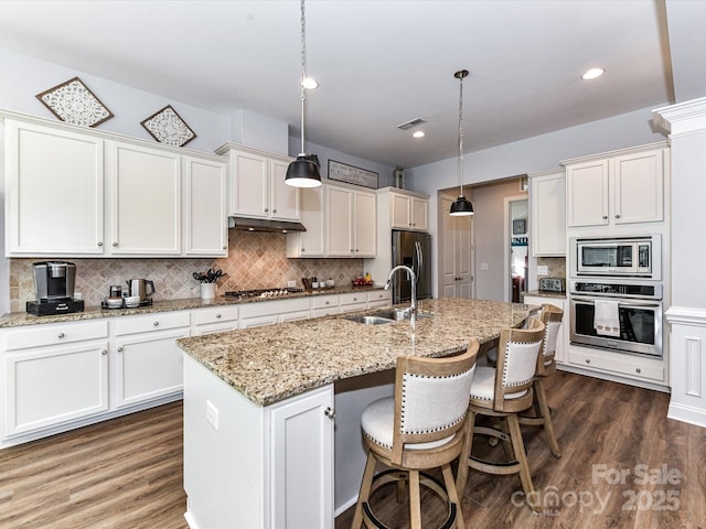 2005 Arbor Hills Dr, Indian Trail, NC 28079 - kitchen featuring appliances with stainless steel finishes, backsplash, dark wood finished floors, white cabinetry, and a kitchen bar
