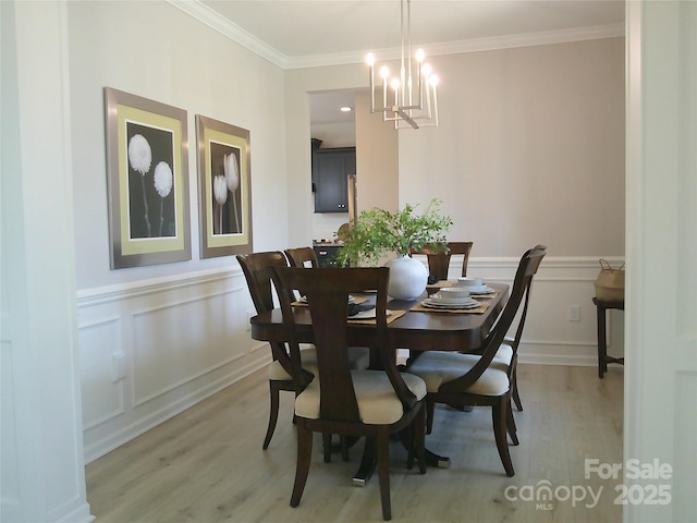 1141 Overlake Dr, Belmont, NC 28012 - dining space featuring light wood-style floors, a chandelier, crown molding, and a wainscoted wall