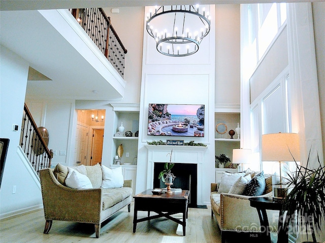 1141 Overlake Dr, Belmont, NC 28012 - living room with a chandelier, stairs, wood finished floors, a towering ceiling, and built in shelves