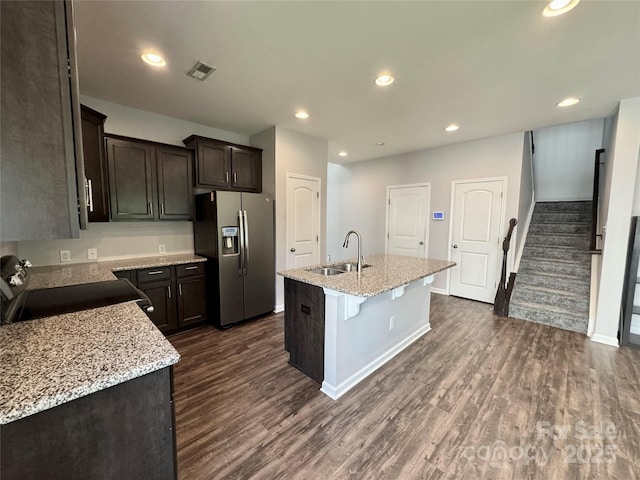 11109 Pond Valley Ct, Charlotte, NC 28269 - kitchen featuring appliances with stainless steel finishes, dark wood-type flooring, a kitchen island with sink, dark brown cabinetry, and light stone countertops