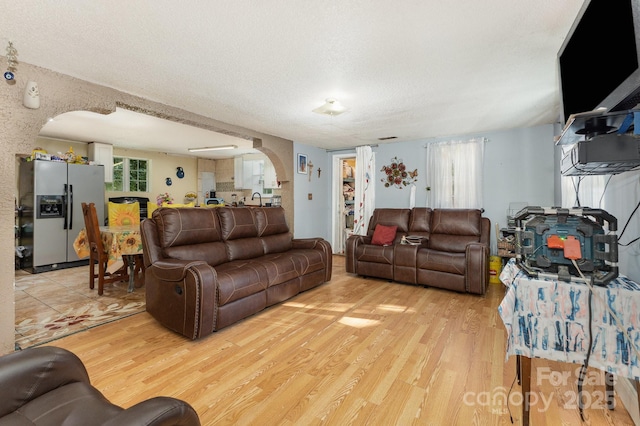 8301 Pine Oak Rd, Waxhaw, NC 28173 - living room with arched walkways, light wood-style floors, and a textured ceiling