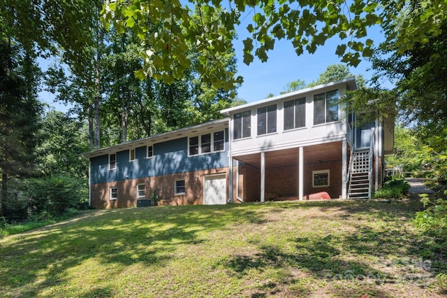 104 Britton Ave, Hendersonville, NC 28791 - rear view of house with a sunroom, brick siding, stairway, and a yard