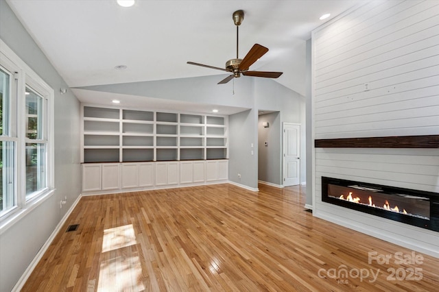 104 Britton Ave, Hendersonville, NC 28791 - unfurnished living room featuring lofted ceiling, a large fireplace, light wood-style floors, built in shelves, and a ceiling fan