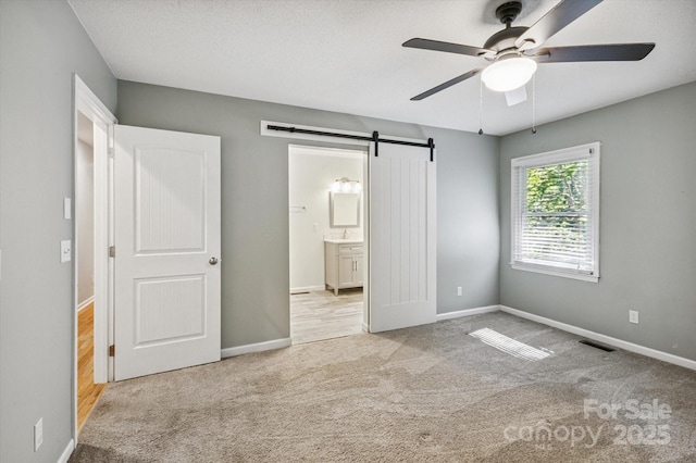 104 Britton Ave, Hendersonville, NC 28791 - unfurnished bedroom with a barn door, carpet floors, connected bathroom, and a ceiling fan