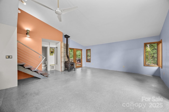 27 Rosebud Ln, Fairview, NC 28730 - unfurnished living room with a wood stove, high vaulted ceiling, a ceiling fan, speckled floor, and stairs