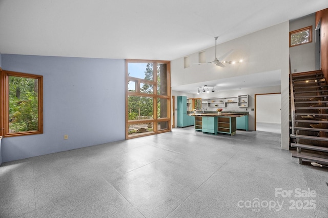 27 Rosebud Ln, Fairview, NC 28730 - unfurnished living room featuring healthy amount of natural light, speckled floor, stairway, and a towering ceiling