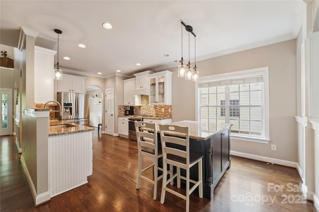 1237 Saint Johns Ave, Matthews, NC 28104 - kitchen with stainless steel appliances, crown molding, arched walkways, light stone countertops, and tasteful backsplash