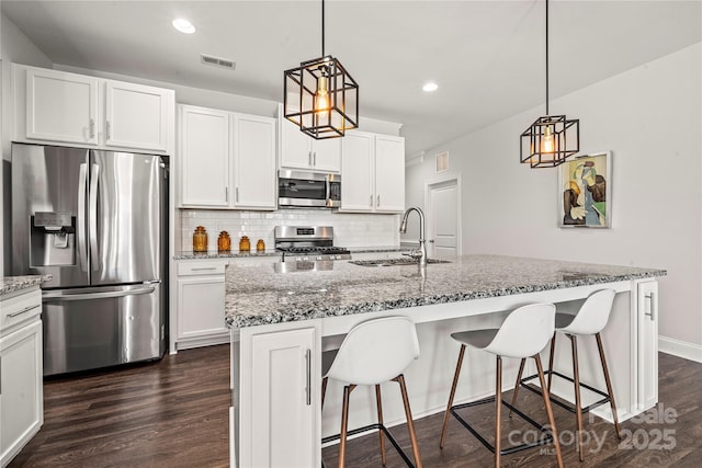 1009 Kemp Rd, Indian Trail, NC 28079 - kitchen featuring appliances with stainless steel finishes, backsplash, dark wood-style flooring, a breakfast bar, and light stone counters