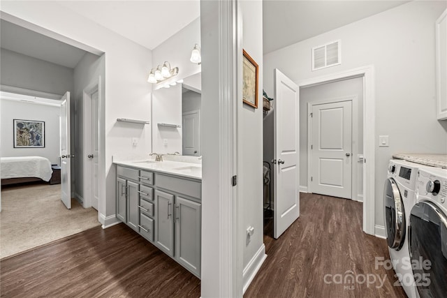 1009 Kemp Rd, Indian Trail, NC 28079 - ensuite bathroom featuring washing machine and clothes dryer, wood finished floors, and double vanity