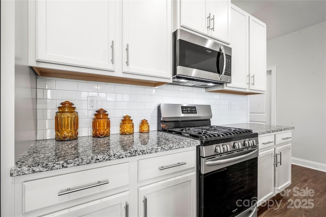 1009 Kemp Rd, Indian Trail, NC 28079 - kitchen featuring stainless steel appliances, light stone counters, white cabinetry, dark wood-style flooring, and backsplash