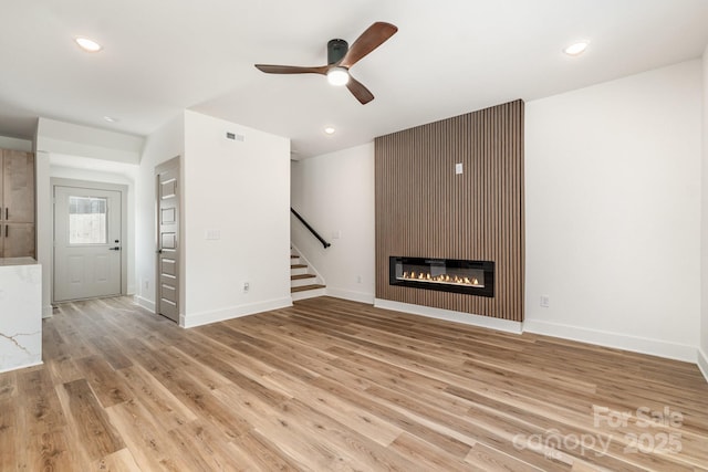 101 Bryan St, Kannapolis, NC 28083 - unfurnished living room with stairs, light wood finished floors, a ceiling fan, a fireplace, and recessed lighting