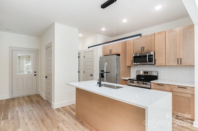 177 Georgia St SW, Concord, NC 28025 - kitchen with appliances with stainless steel finishes, light wood-style flooring, an island with sink, tasteful backsplash, and light countertops