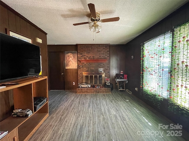 6708 Nutcracker Pl, Charlotte, NC 28212 - unfurnished living room featuring wood finished floors, a textured ceiling, a ceiling fan, a brick fireplace, and wooden walls