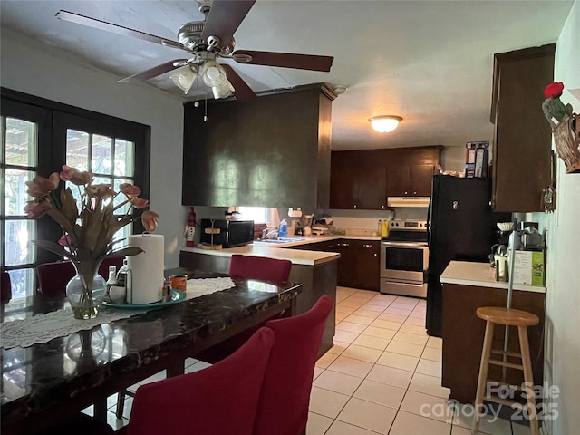 6708 Nutcracker Pl, Charlotte, NC 28212 - kitchen with stainless steel electric range oven, light tile patterned flooring, under cabinet range hood, dark brown cabinetry, and a ceiling fan