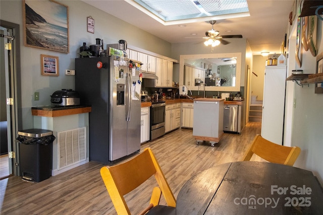 2668 Reedy Branch Rd, Purlear, NC 28665 - kitchen featuring stainless steel appliances, ceiling fan, light wood-type flooring, under cabinet range hood, and dark countertops