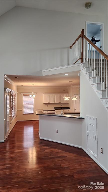 10607 Old Bridge Ln, Charlotte, NC 28269 - kitchen featuring a chandelier, dark wood-style floors, high vaulted ceiling, dark countertops, and a peninsula