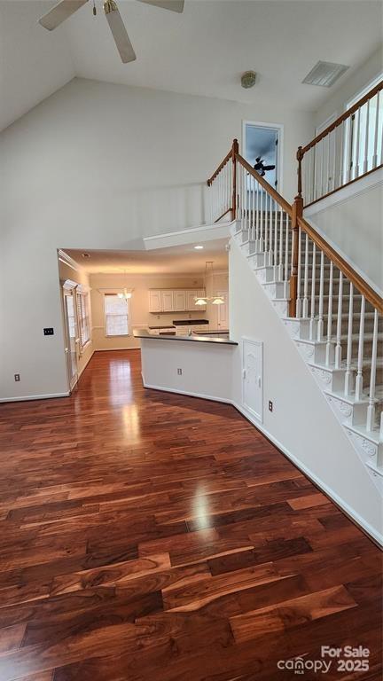 10607 Old Bridge Ln, Charlotte, NC 28269 - unfurnished living room featuring ceiling fan, high vaulted ceiling, stairs, wood finished floors, and a chandelier