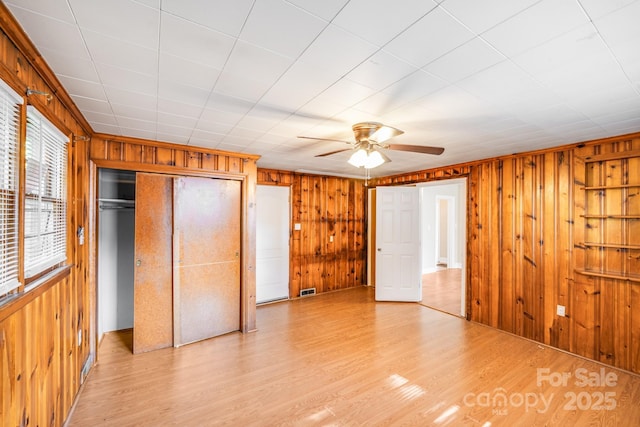 2405 Greenland Ave, Charlotte, NC 28208 - unfurnished bedroom featuring wood walls, light wood-style floors, a closet, and a ceiling fan